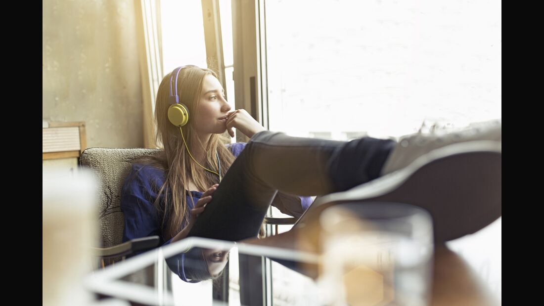 Relaxed young woman sitting on a chair wearing headphones