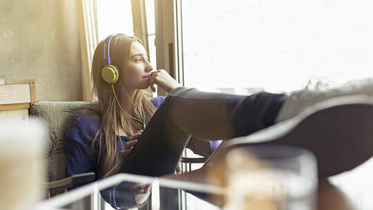 Relaxed young woman sitting on a chair wearing headphones
